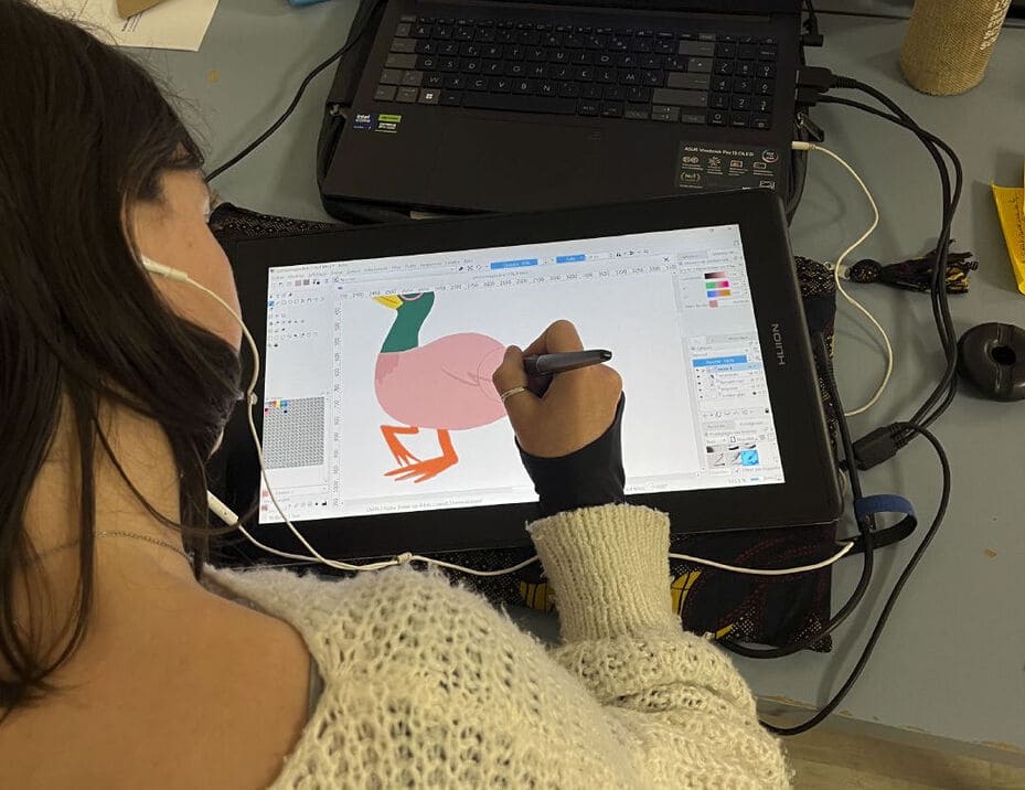 Photo représentant Lise, vue de haut, en train de dessiner un canard sur sa tablette graphique.