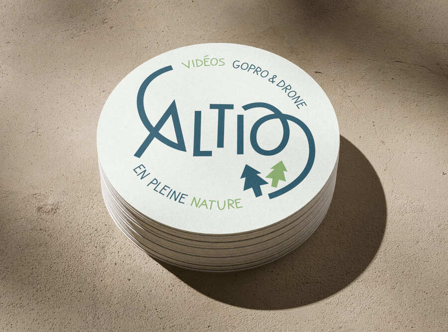 Photo d'un paquet de cartes de visites en format rond. On ne voit que la première carte, sur laquelle est présente le logo Altio, d'une chaîne Youtube de « vidéos Go Pro et drone en pleine nature » dont le A et le O forment des courbes aériennes.