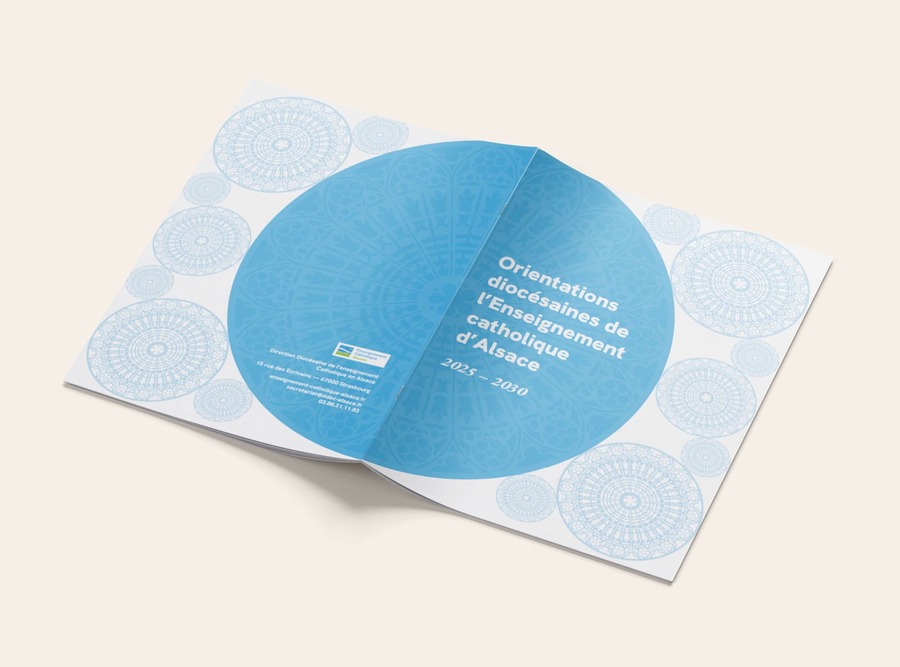 Magazine ouvert à l'envers sur un fond neutre. On y voit des plusieurs rosaces bleu ciel et le titre du document : Orientations diocésaines de l'Enseignement catholique d'Alsace 2025-2026.