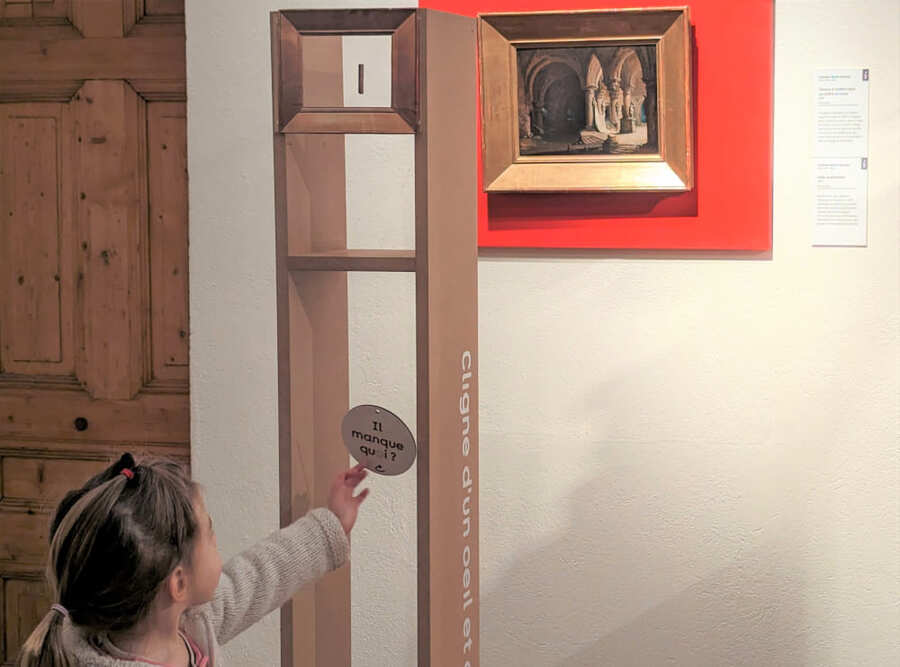 Dispositif en bois placé devant une œuvre muséale qui met en avant l'absence d'un poteau dans le tableau.